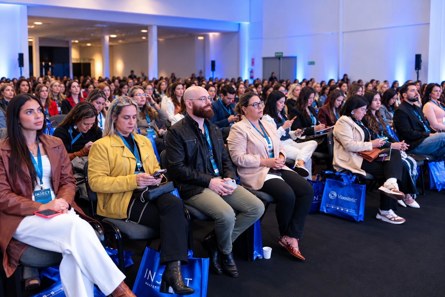 Plateia lotada em um evento da Viaestetic, com sacolas personalizadas INJECT e Viaestetic
